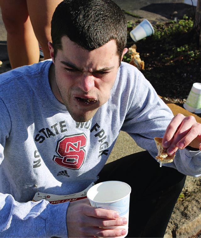 Rapaz com a boca cheia de donuts, na corrida do donut