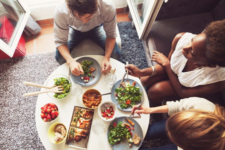 Amigos vegetarianos comendo em volta da mesa