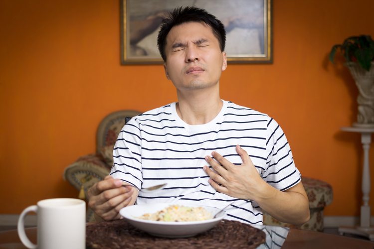 Homem sentindo azia e refluxo ao comer