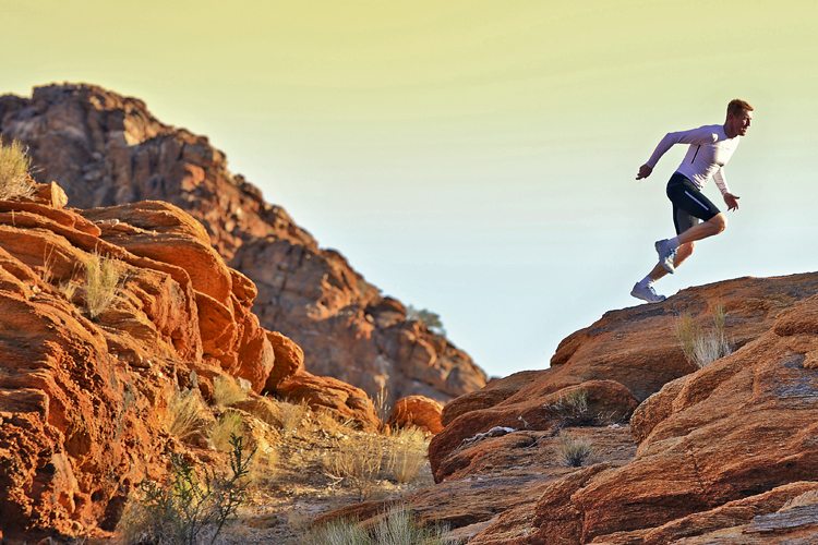 Homem subindo montanha em trail running